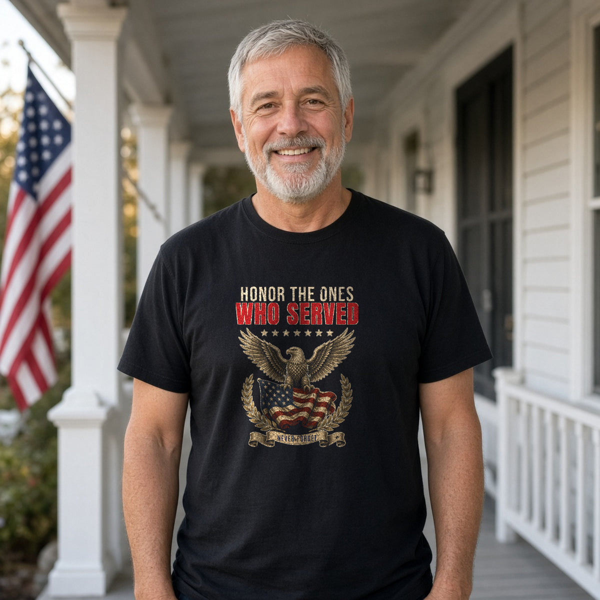 Man in a black tee with a vintage eagle and flag design reading Honor The Ones Who Served and Never Forget, standing on a farmhouse porch