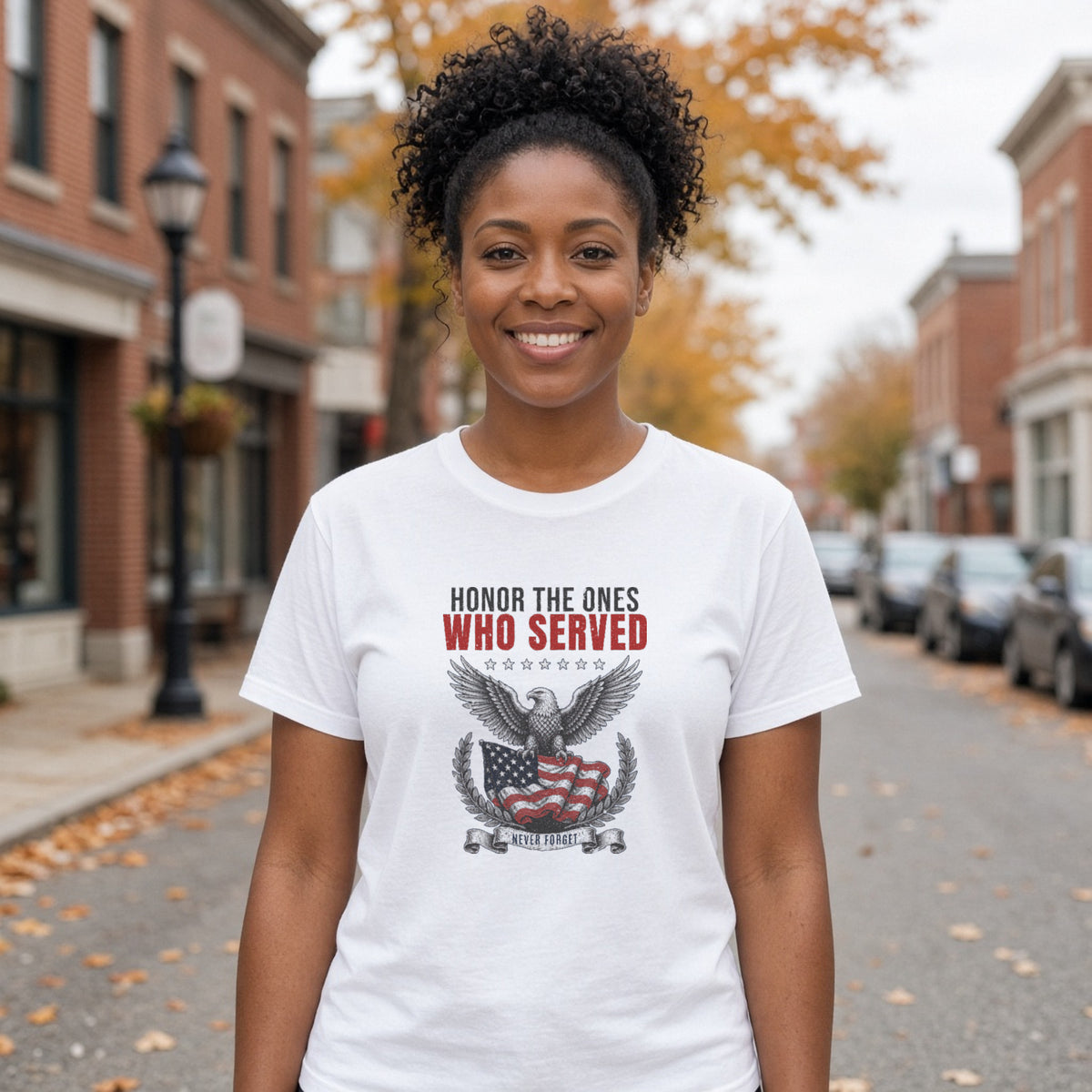 Woman in a white tee with a vintage navy and red eagle and flag design reading Honor The Ones Who Served and Never Forget, standing on a farmhouse porch
