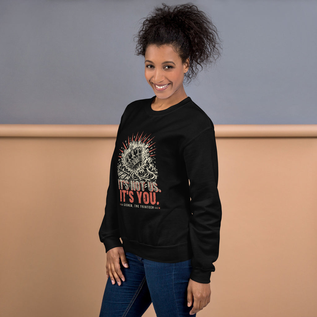 Woman wearing the black It's Not Us, It's You sweatshirt, crown-in-the-sea print on the chest, three-quarter view.