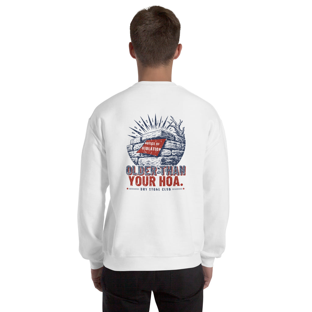 Man seen from behind in the white Older Than Your HOA sweatshirt, navy and red stone wall print across the upper back.
