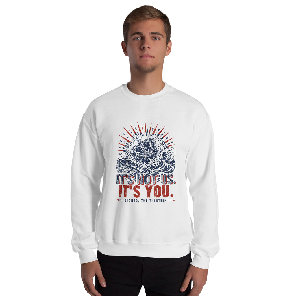 Man wearing the white It's Not Us, It's You sweatshirt, front view, navy and red crown-in-the-waves print on the chest.