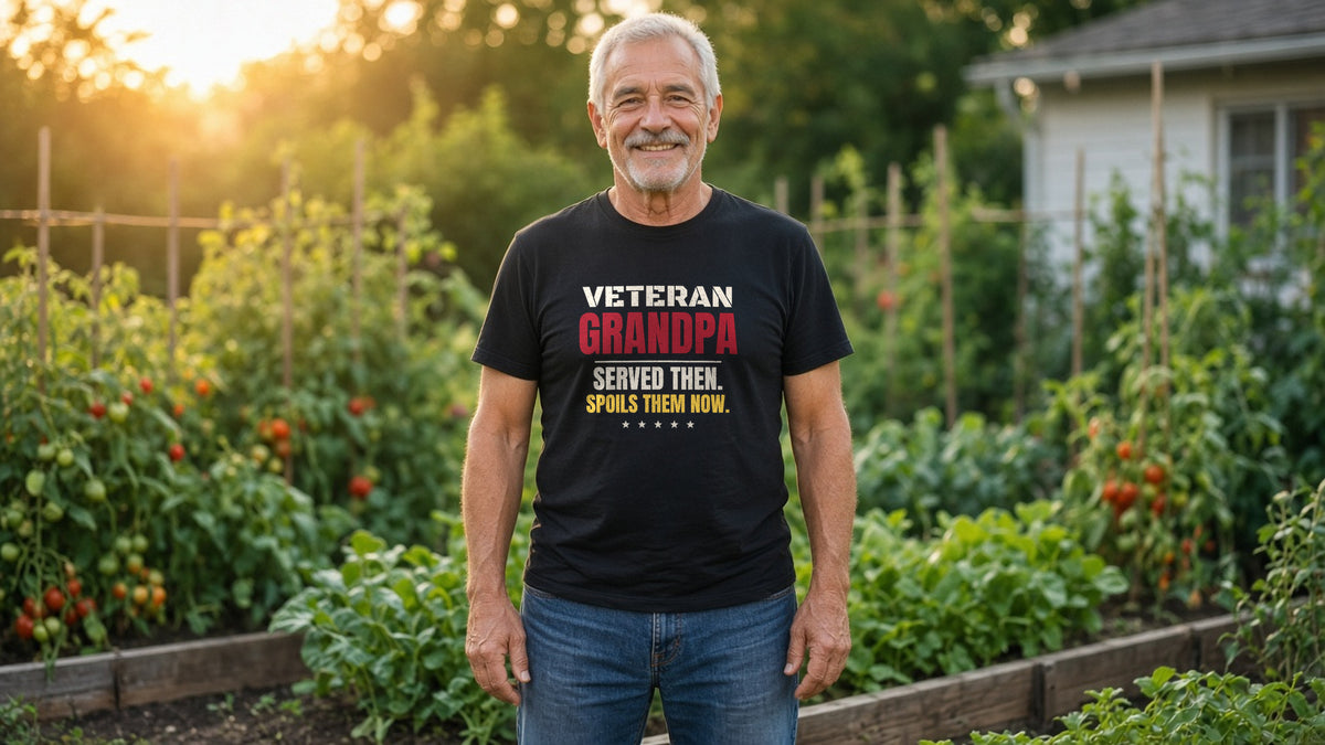 Smiling grandfather in a black Veteran Grandpa tee in a vegetable garden while his grandkids play behind him
